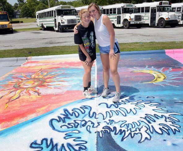 High Point Central seniors Ashley Anne Combs, left and Emmy Weiland stand in their parking spaces that they personalized by painting a colorful design of a sun and a moon. The seniors spent about a week to complete their artwork.
